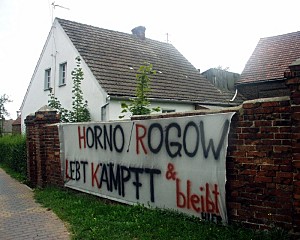 Protestplakat an einer Hofmauer mit der Aufschrift: HORNO/ROGOW LEBT KÄMPFT & BLEIBT