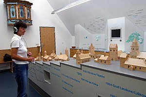 Eine Ausstellungsbesucherin betrachtet die Holzmodelle der devastierten Kirchen.