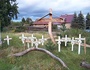Viele kleine weiße Holzkreuze beschriftet mit  Ortsnamen wurden auf einer Wiese aufgestellt.