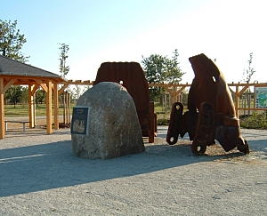 Gedenkstein umgeben von zwei Baggerschaufeln und Gedenktafeln
