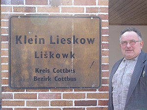 Ein Umsiedler neben dem Alten Ortsschild "Klein Lieskow"