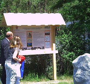 Gezeigt werden Besucher der Erinnerungsstätte vor der Gedenktafel und dem Gedenkstein. 