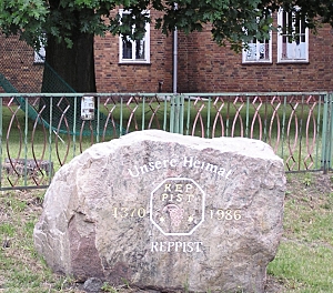 Der Gedenkstein vor dem  Kulturhaus mit der Inschrift "Unsere Heimat Reppist 1370 - 1986". In der Mitte der Inschrift ist das Gemeindesiegel dargestellt.