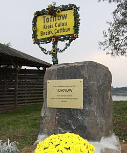 Blick zum neuen Tornoer Gedenkstein und einem geschmückten ehemaligem Ortsschild von Tornow