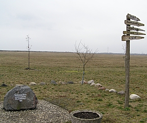 Erinnerungsstätte mit Wegweiser in Richtung zum ehemaligen  Dorf und Gedenkstein. Auf dem Stein steht: Erinnerung an die Überbaggerung des Dorfkerns 1986