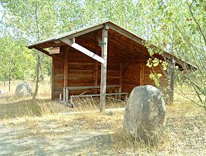 Schutzhütte mit Sitzplätzen umgeben von Laubbäumen und Findlingen Schutzhütte mit Sitzplätzen umgeben von Laubbäumen und Findlingen
