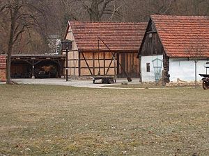 Der Ziehbrunnen umgeben von einem Wohn-Stallhaus, einer Scheune und einem Taubenständer.